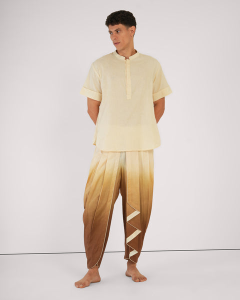 Man standing in Cinnamon Ombre YogaFlow set — natural linen-cotton kurta with pleated dhoti pants, poised in quiet presence.