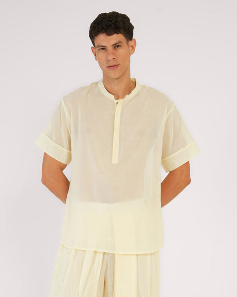 Man standing in sheer white YogaFlow top — 100% cotton, airy and minimal, blending quiet clarity with soft drape.