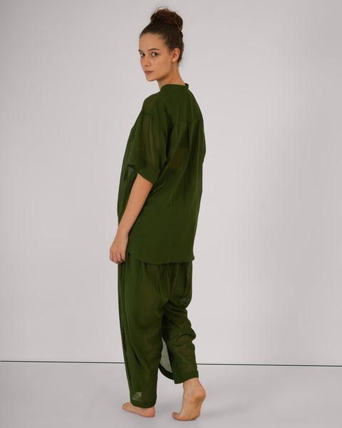Female model turned partially back, wearing Mehndi green cotton yoga set, highlighting breathable natural fabric, white studio background.