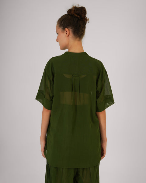 Female standing with back turned, showcasing Mehndi green cotton yoga top, breathable natural fabric, white studio background.