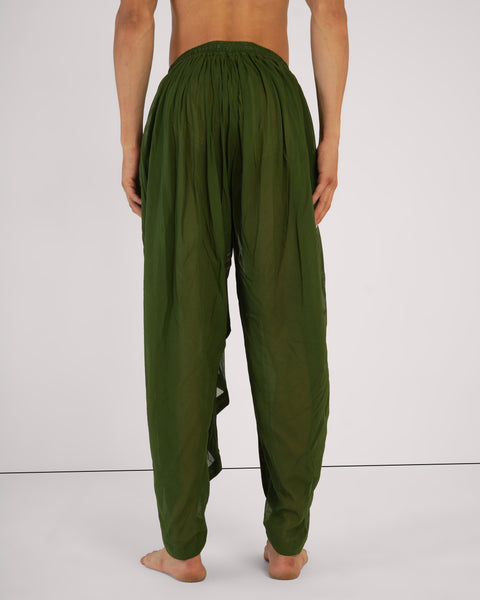 Rear view of male standing straight wearing Mehndi green cotton yoga pants, elastic waistband, breathable natural fabric, white studio background.