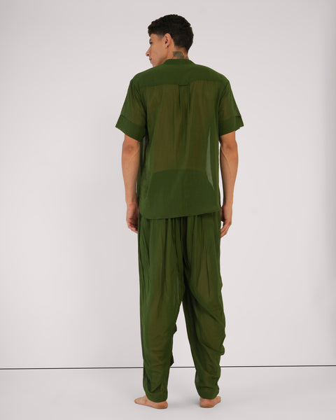 Male facing away, standing casually, showcasing Mehndi green cotton yoga set, breathable natural fabric, white studio background.