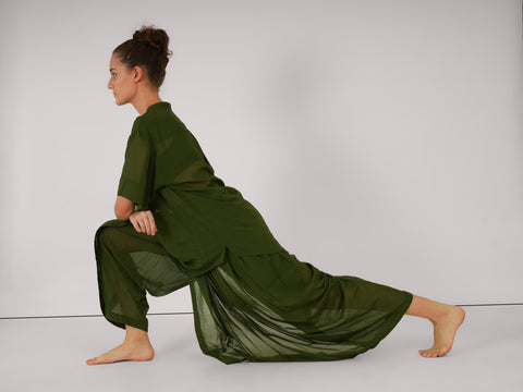 Female performing yoga lunge wearing Mehndi green cotton yoga set, breathable natural fabric, side profile, white studio background.