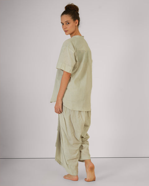 Female turning partially back in Vibhuti Grey linen cotton yoga set, side-view showcasing breathable natural fabric, white studio background.
