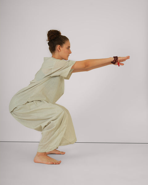 Female model performing chair pose yoga asana, wearing Vibhuti Grey linen cotton yoga set, breathable natural fabric, white studio background.