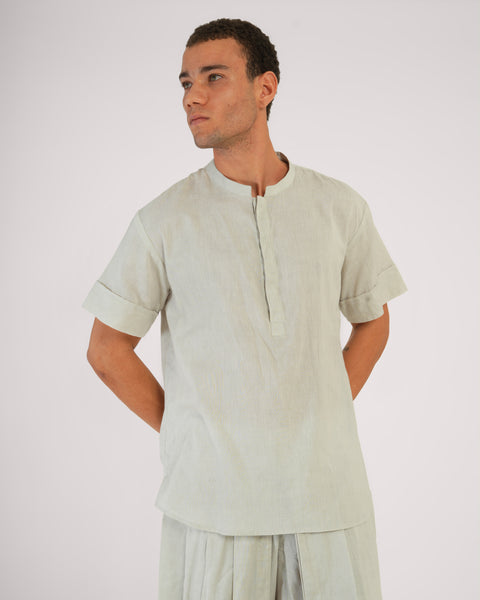 Front close-up of male model standing relaxed wearing Vibhuti Grey linen cotton yoga top, breathable natural fabric, white studio background.