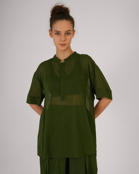Female facing forward, close-up view, wearing Mehndi green cotton yoga top, breathable natural fabric, white studio background.