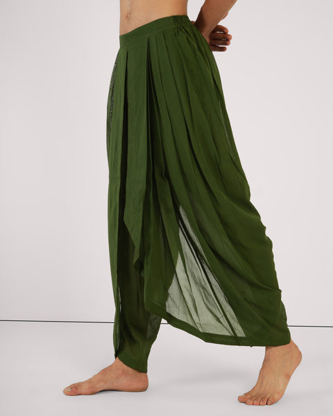 Side view of male model stepping forward, Mehndi green cotton yoga pants, showcasing drape, breathable natural fabric, white studio background.