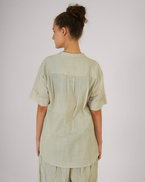 Rear close-up view of female model standing casually, showcasing Vibhuti Grey linen cotton yoga top, breathable natural fabric, white studio background.