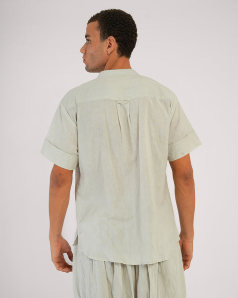 Rear close-up view of male standing casually, wearing Vibhuti Grey linen cotton yoga top, breathable natural fabric, white studio background.